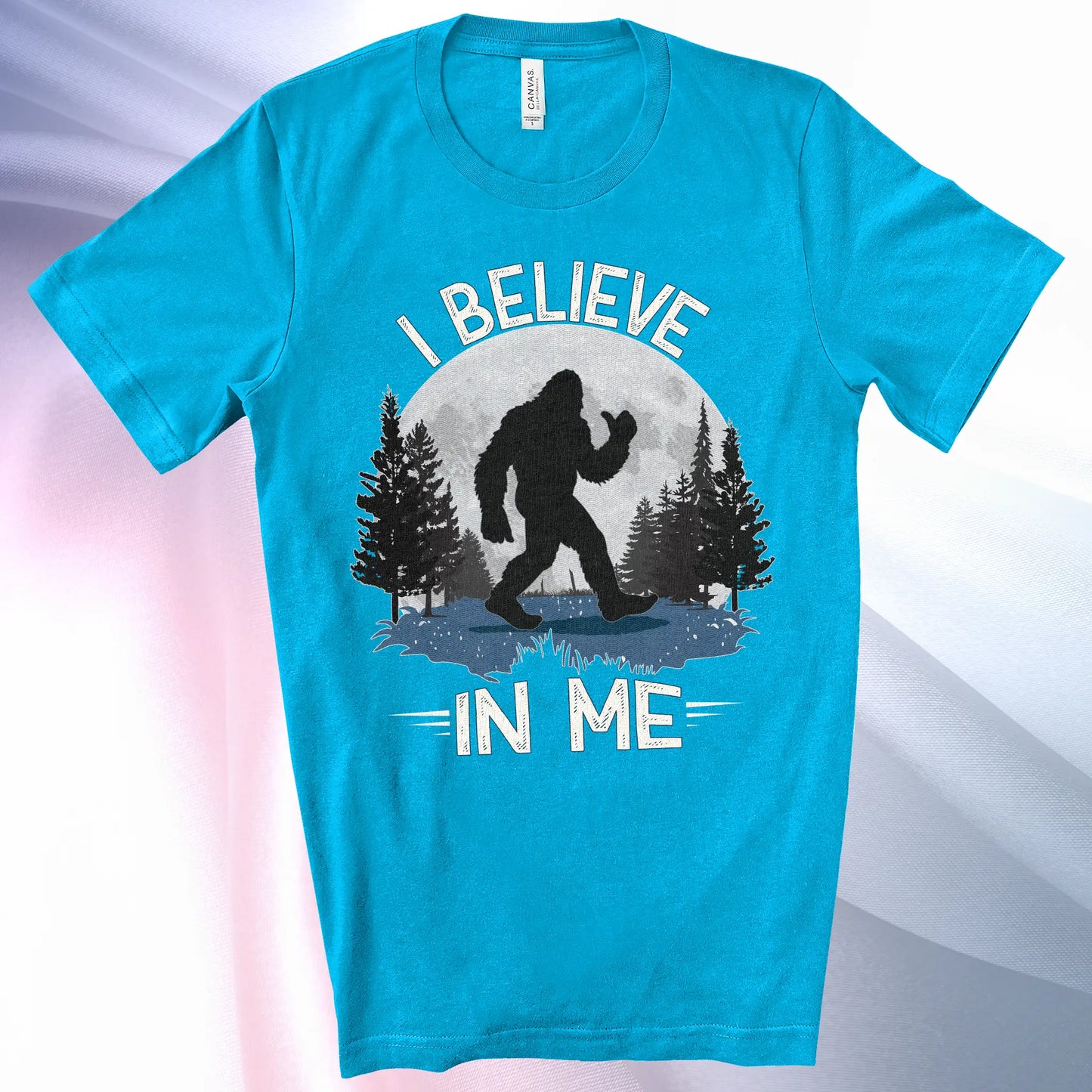 Aqua colored Bigfoot Believes T-Shirt with Bigfoot's silhouette in a moonlit forest and I Believe at the top and In Me below