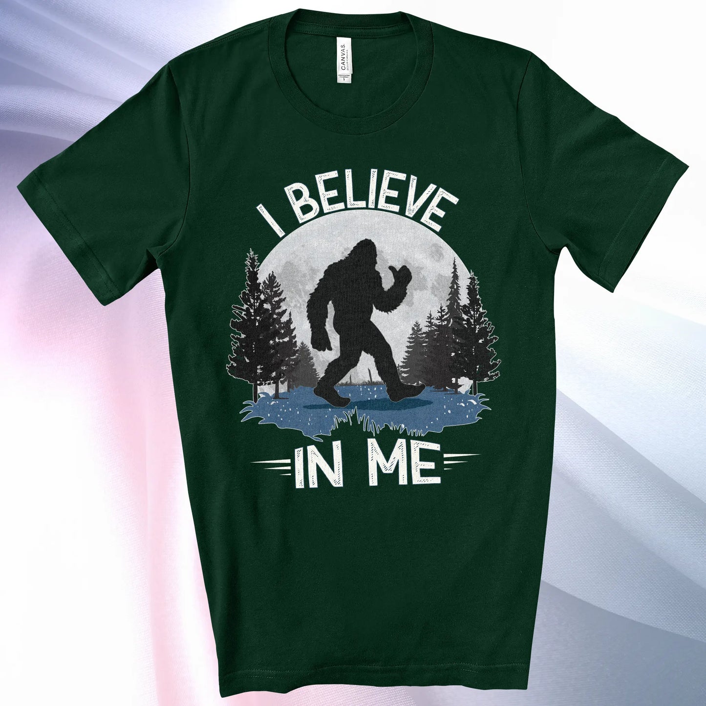 Forest colored Bigfoot Believes T-Shirt with Bigfoot's silhouette in a moonlit forest and I Believe at the top and In Me below