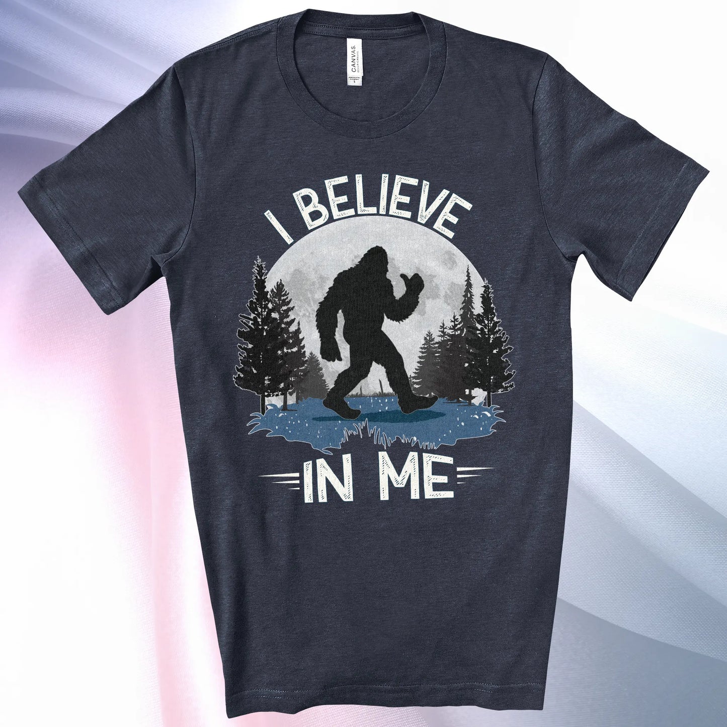 Heather Navy Bigfoot Believes T-Shirt with Bigfoot's silhouette in a moonlit forest and I Believe at the top and In Me below