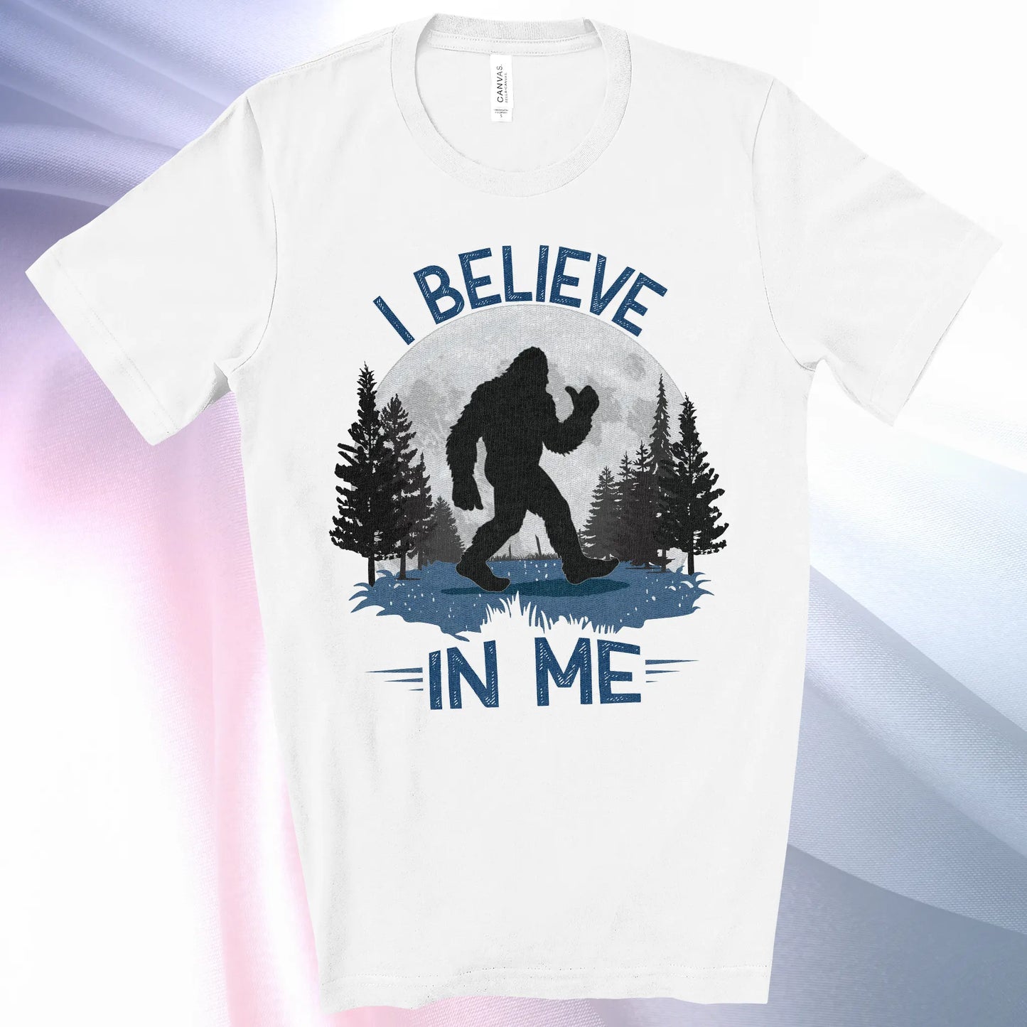 White colored Bigfoot Believes T-Shirt with Bigfoot's silhouette in a moonlit forest and I Believe at the top and In Me below