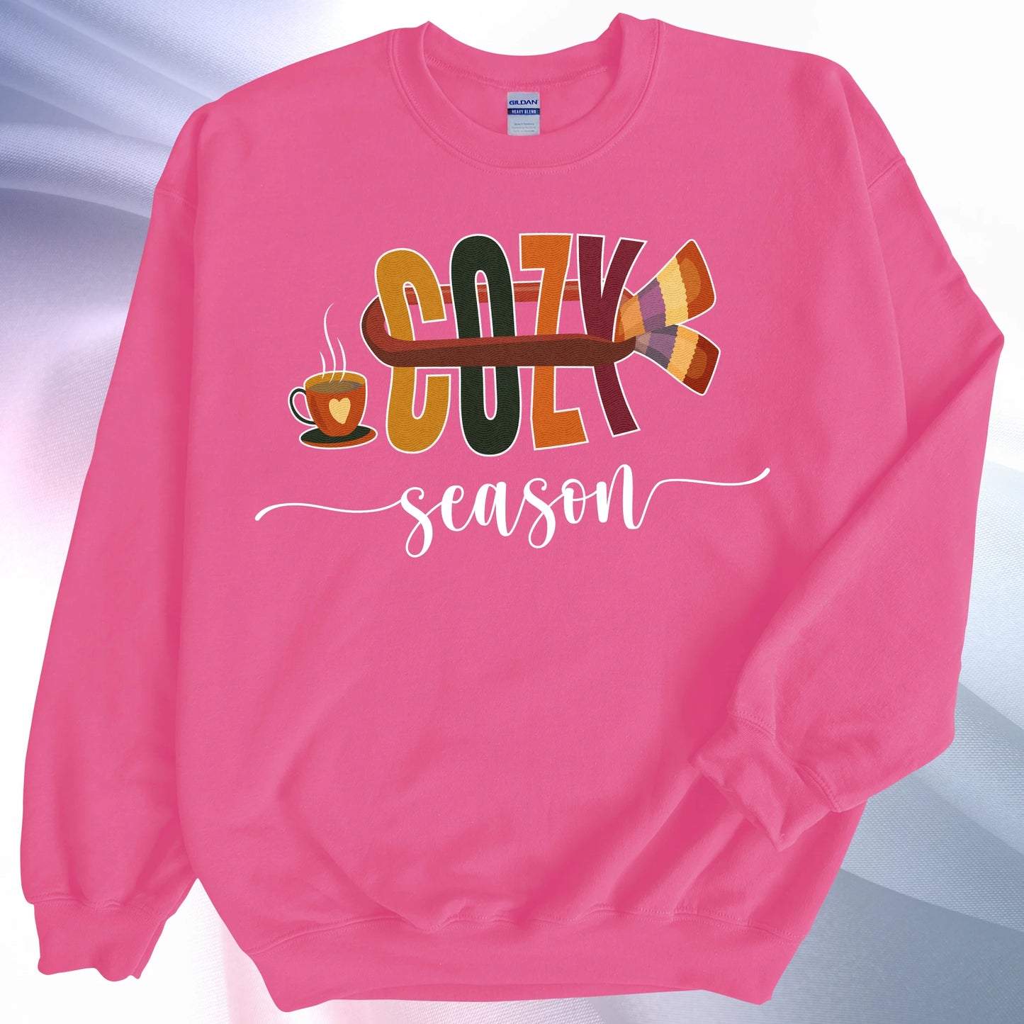 Heliconia colored Cozy Season sweatshirt, on colorful gradient silk background. Sleeve folded over the garment at the elbow