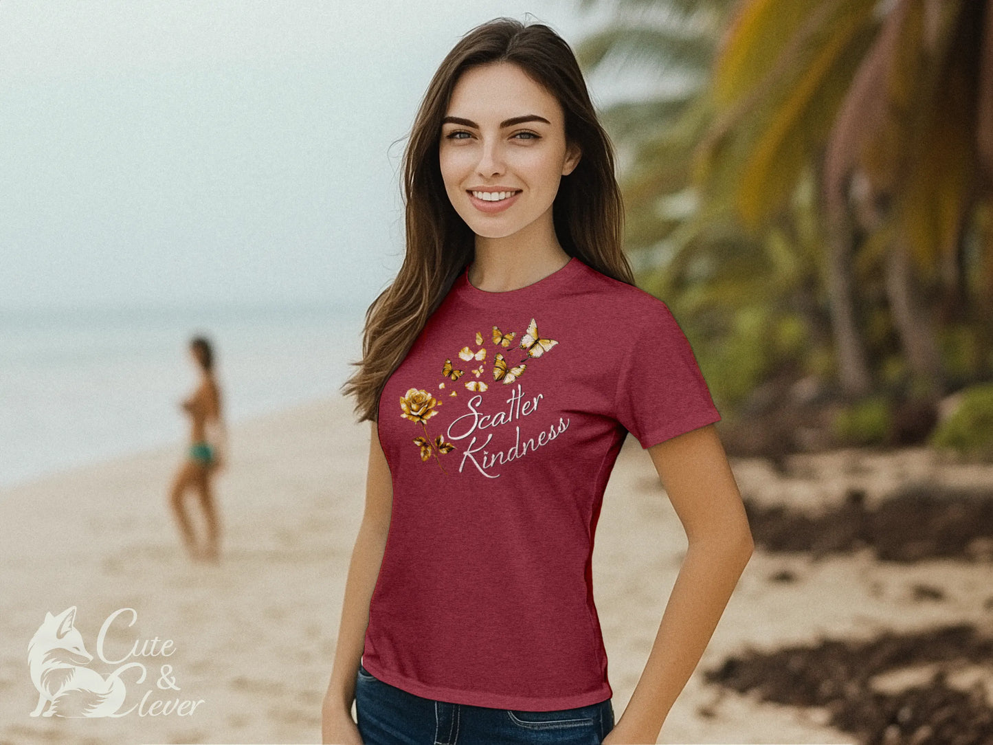 Woman smiles while wearing a Heather Raspberry colored Scatter Kindness T-Shirt while standing outdoors on a tropical beach.