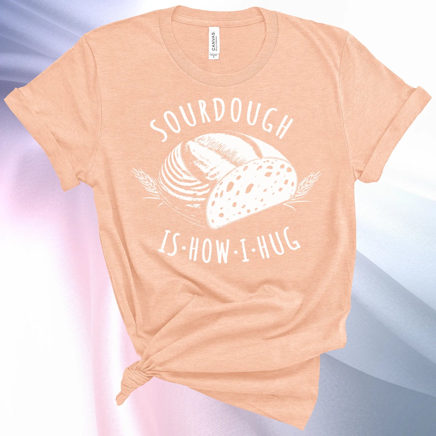 Heather Peach colored Sourdough Hug T-Shirt featuring a loaf of sourdough and "Sourdough" above and "Is How I Hug" below