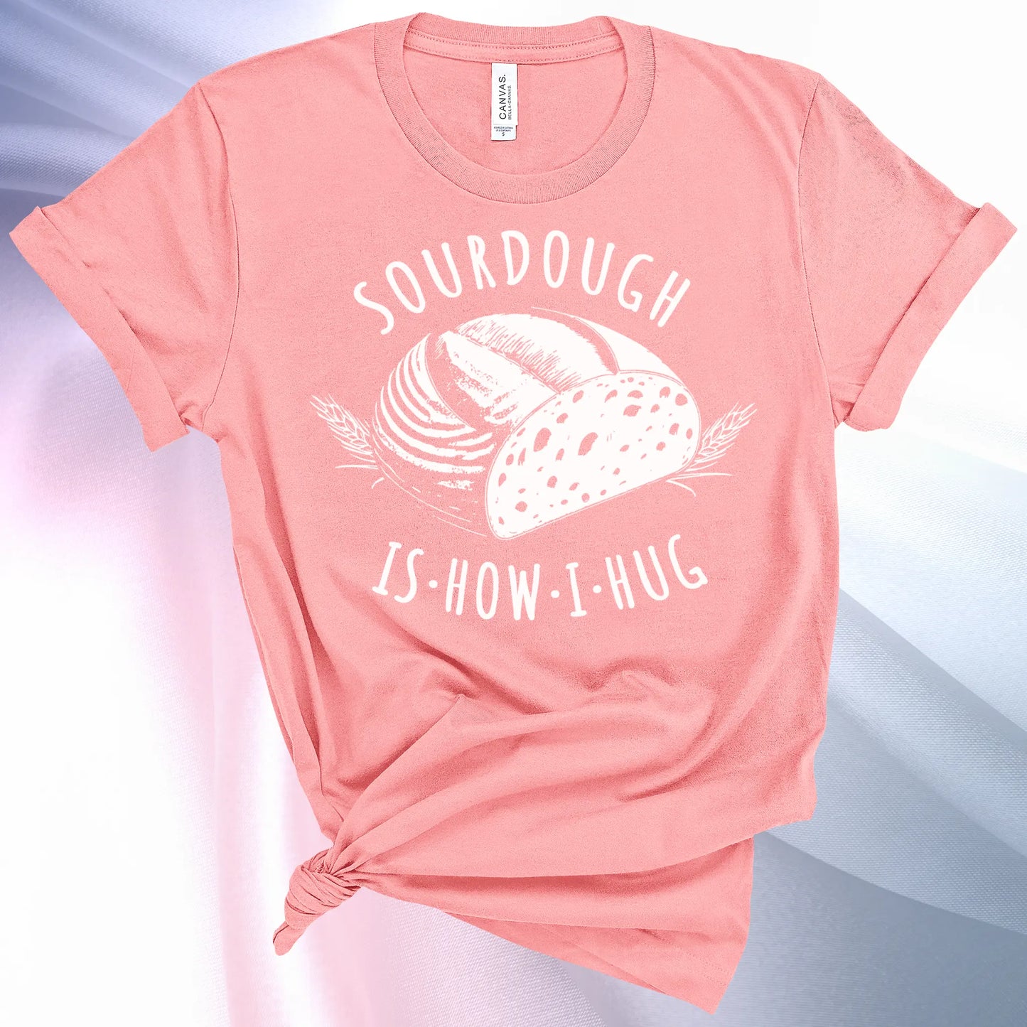Pink colored Sourdough Hug T-Shirt featuring a loaf of sourdough and "Sourdough" above and "Is How I Hug" below