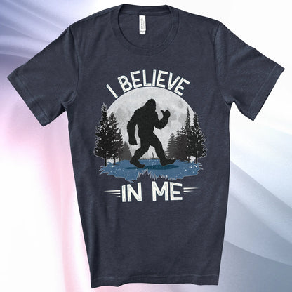Heather Navy Bigfoot Believes T-Shirt with Bigfoot's silhouette in a moonlit forest and I Believe at the top and In Me below