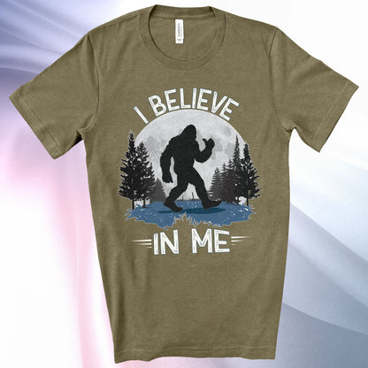 Heather Olive Bigfoot Believes T-Shirt with Bigfoot's silhouette in a moonlit forest and I Believe at the top and In Me below
