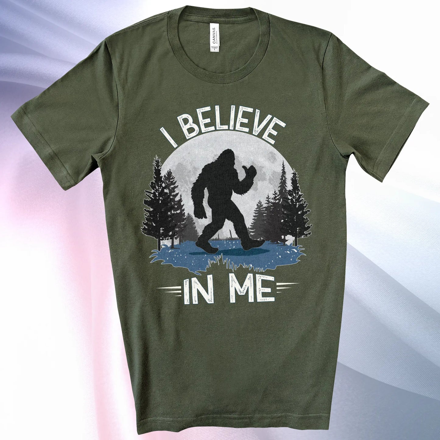 Military Green Bigfoot Believes T-Shirt with Bigfoot's silhouette in a moonlit forest and I Believe at the top and In Me below