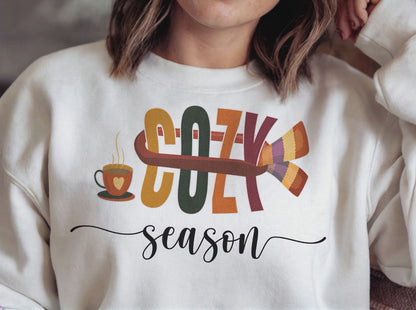 Relaxed woman in white Cozy Season sweatshirt smiles, camera pans to fall leaves, then fades back to show her sipping coffee