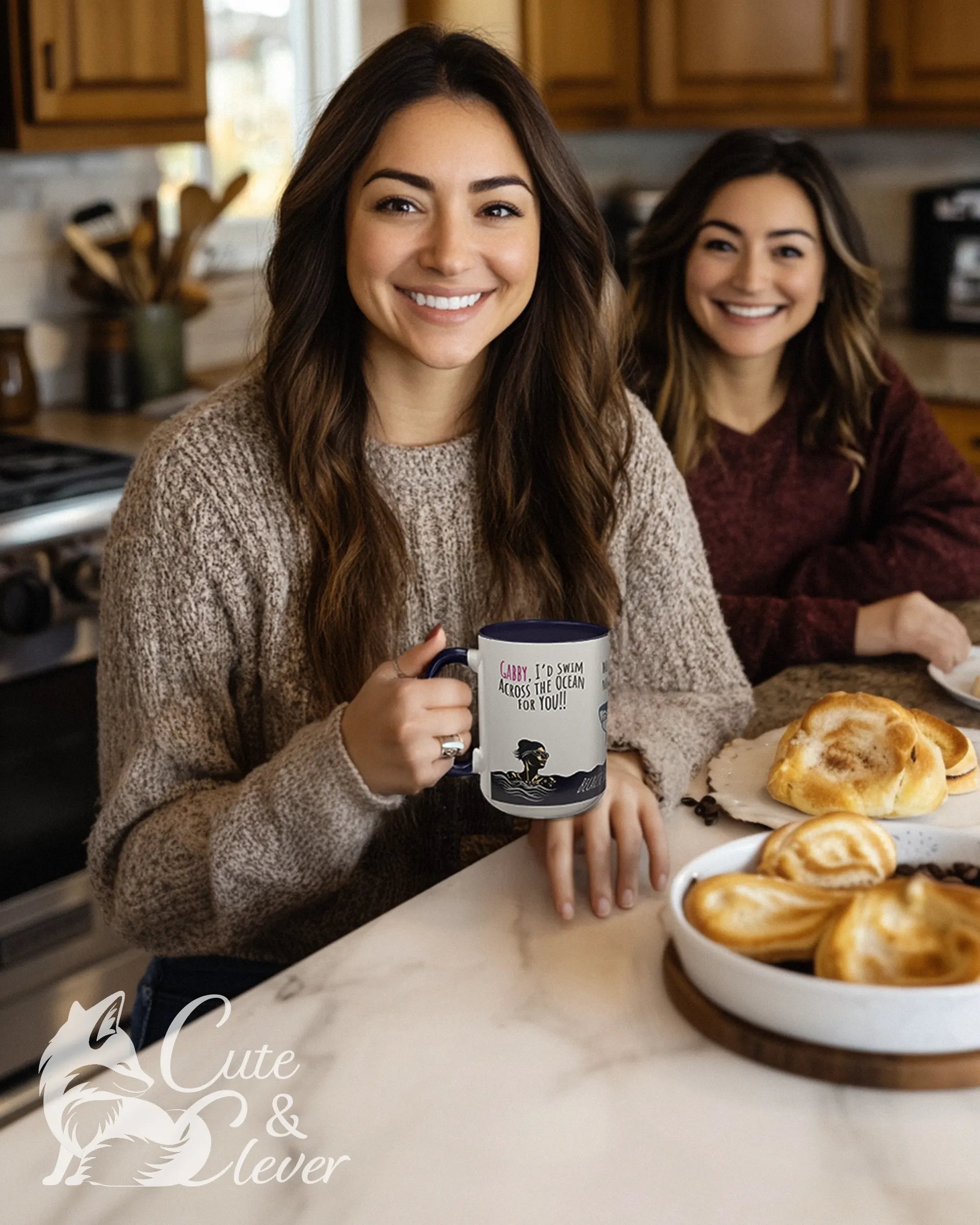 Two women at a kitchen counter, one holding a Navy colored Swim the Ocean 15Oz Premium Accent Mug gift.